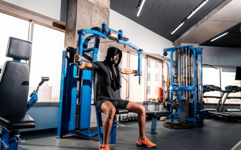 Athletic man working out on a chest fly machine in a modern gym in Bahrain.