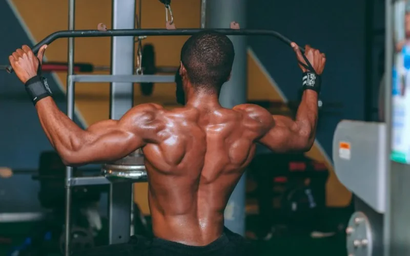Strong athletic man performing pull-up exercise in a gym, showcasing muscular back.