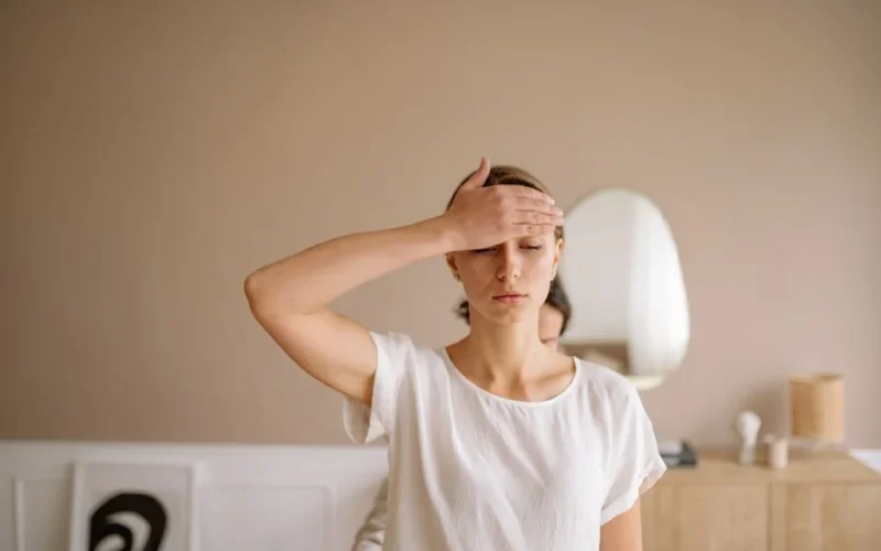 Woman practicing mindfulness meditation with hand on forehead indoors.