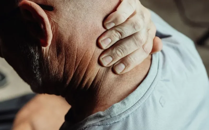 Man with neck pain holding his neck in discomfort, conveying tension or stress.