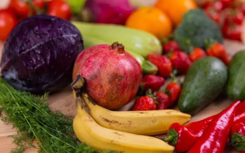 A variety of fresh fruits and vegetables arranged beautifully on a wooden table, showcasing natural nutrition.